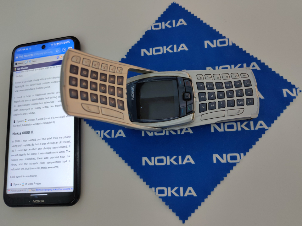My Nokia 6800, halfway between the traditional and QWERTY state. It is lying on a classic Nokia-logo microfiber cleaning cloth. Next to it, on the screen of the Nokia X10, you can see the part of this post about it displayed in a browser.
